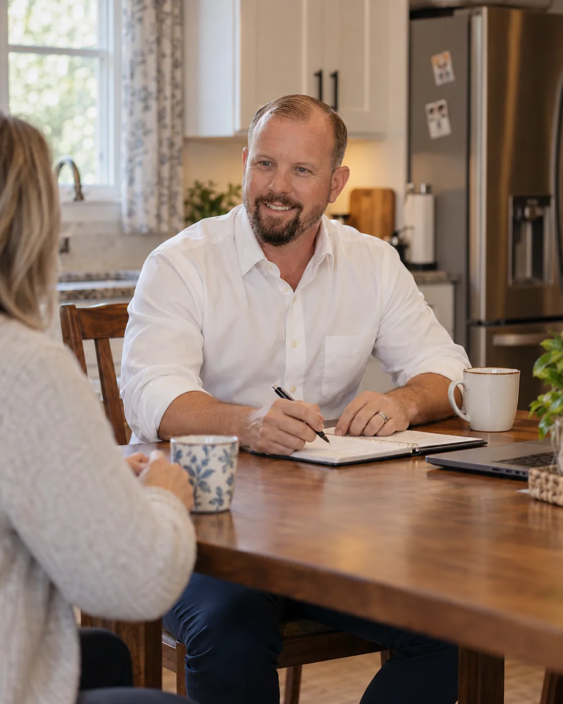 Dave Dempsey taking notes at a kitchen table with a homeowner during a listing consultation in Bryan, Ohio